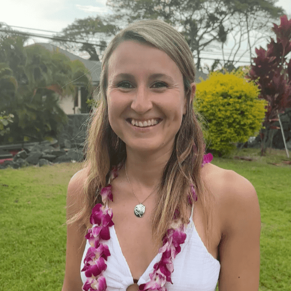 Smiling woman outdoors with a floral lei and necklace.