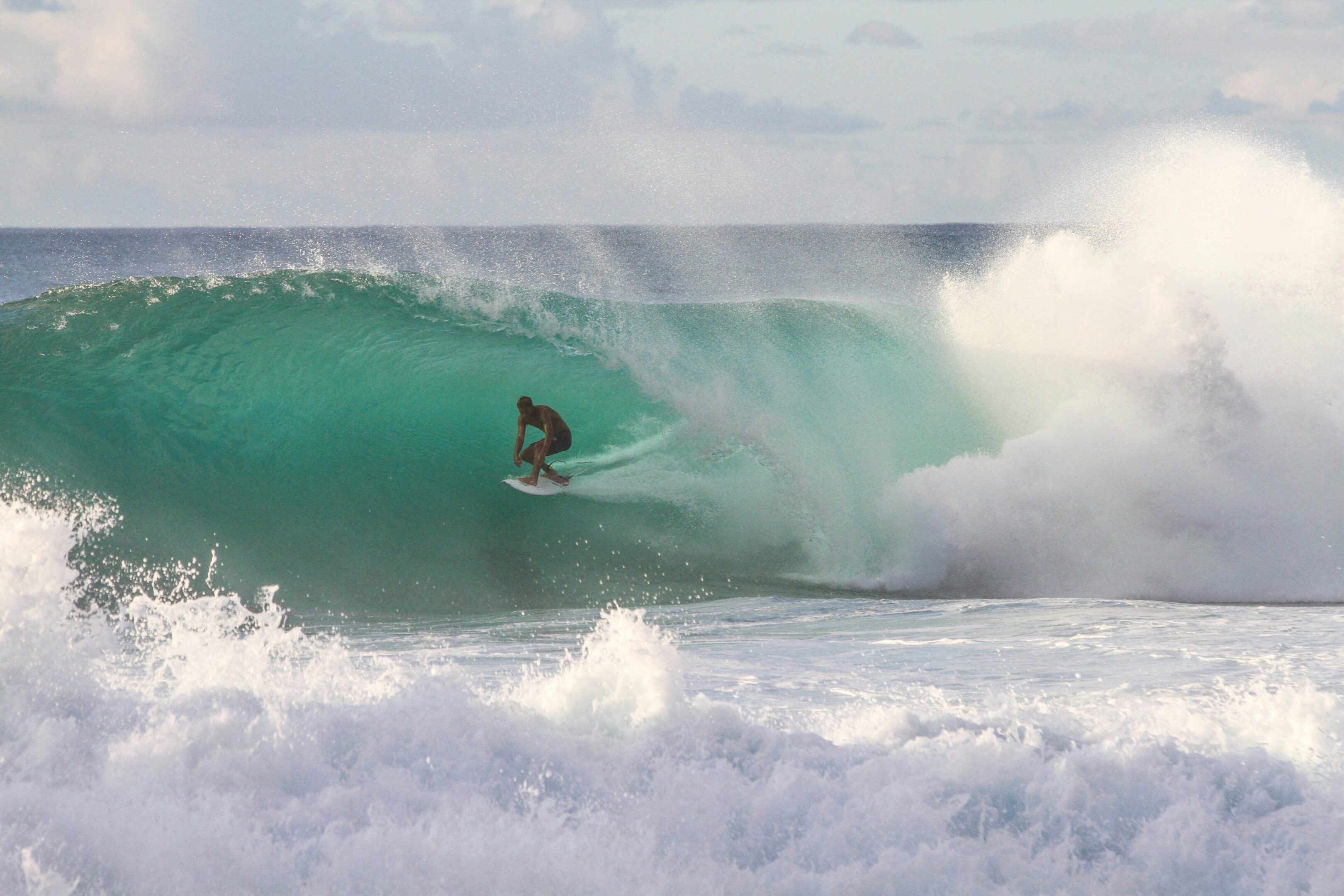 Surfer riding a large ocean wave tube.