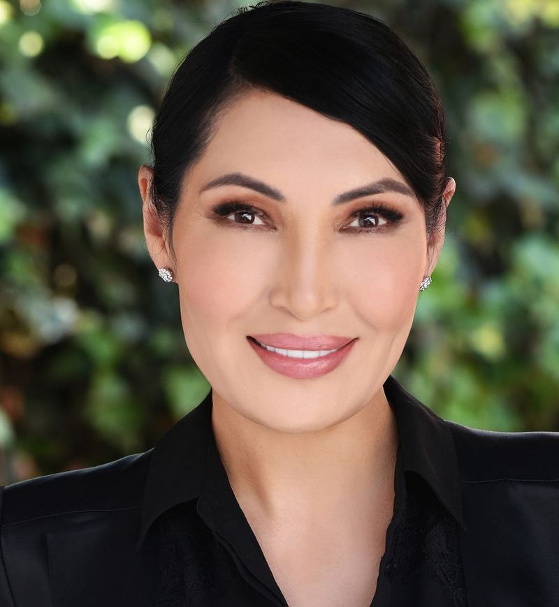 Professional woman smiling outdoors with natural background.
